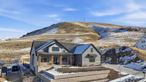 View of front of property featuring a porch, board and batten siding, a shingled roof, stone siding, and a mountain view