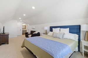 Bedroom with light carpet, vaulted ceiling, recessed lighting, and ensuite bath