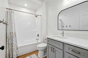Full bath featuring vanity, shower / bath combo, and light wood-style floors