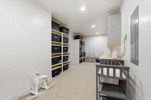Bedroom with light carpet, electric panel, and recessed lighting