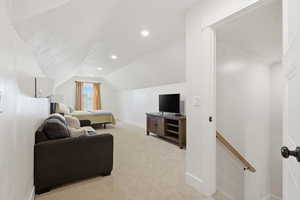 Living area with light colored carpet, vaulted ceiling, and recessed lighting