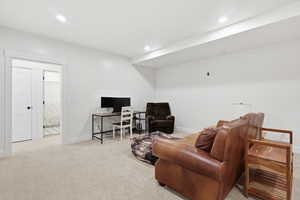 Living area featuring light colored carpet, a desk, and recessed lighting