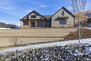 View of front of house with board and batten siding, covered porch, and stone siding