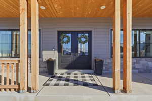 Entrance to property featuring covered porch and stone siding