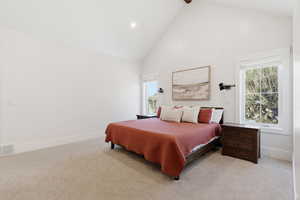 Bedroom with high vaulted ceiling, light colored carpet, and recessed lighting
