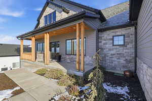 Rear view of house featuring stone siding and covered porch