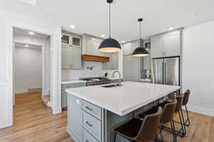 Kitchen with gray cabinetry, a kitchen bar, light wood finished floors, decorative backsplash, and recessed lighting