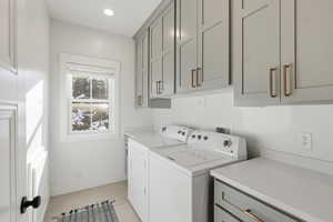 Laundry room with independent washer and dryer, cabinet space, and light wood-style floors