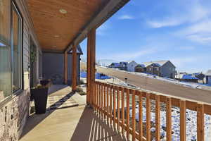 Snow covered back of property with a porch and a residential view