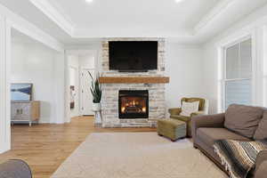 Living area featuring wood-type flooring, a fireplace, and a raised ceiling