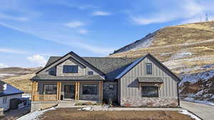 Modern inspired farmhouse with board and batten siding, a mountain view, covered porch, and stone siding