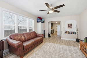 Upstairs Living area featuring light wood-type flooring, a ceiling fan, and arched walkways
