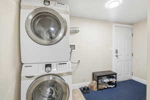 Downstairs Entry/ Laundry featuring stacked washer and dryer and wood finished floors