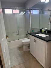 Full bath with vanity, shower / bath combination with glass door, plenty of natural light, and light tile patterned floors