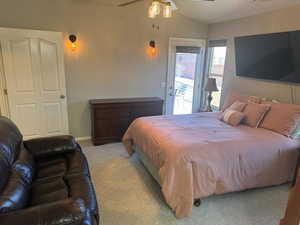Carpeted bedroom featuring access to exterior, vaulted ceiling, and ceiling fan