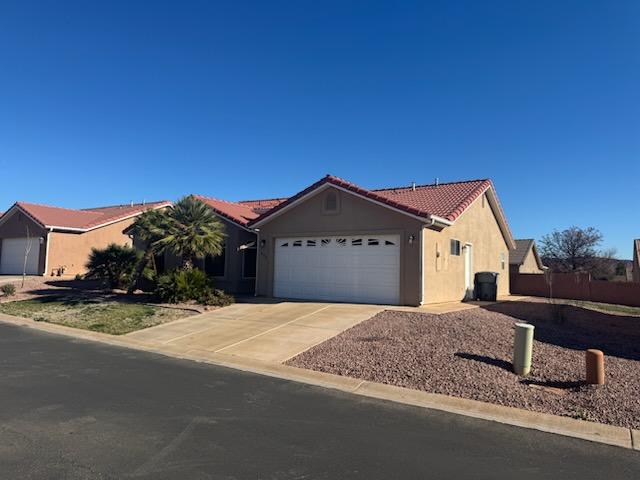 Ranch-style house featuring stucco siding, driveway, a garage, and a tiled roof