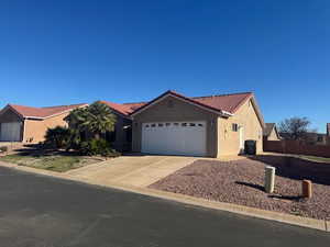 Ranch-style house featuring stucco siding, driveway, a garage, and a tiled roof