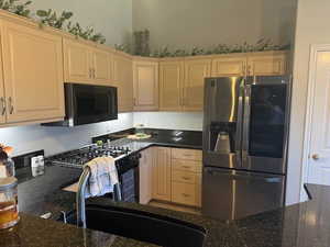 Kitchen with black appliances and dark stone counters