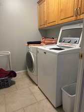 Laundry room with cabinet space, washer and clothes dryer, and light tile patterned floors
