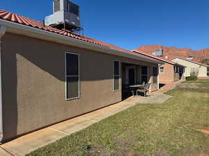 Rear view of house featuring stucco siding, a lawn, a patio, and a tile roof