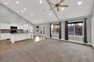Unfurnished living room with high vaulted ceiling, light tile patterned floors, recessed lighting, a ceiling fan, and light carpet