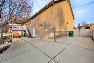View of side of home featuring a gate, a wooden deck, stucco siding, and stairs