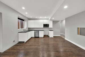 Kitchen with white cabinetry, recessed lighting, stainless steel appliances, dark wood-style floors, and dark countertops