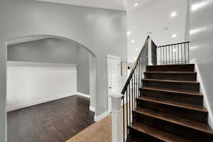 Stairway with wood finished floors, arched walkways, and recessed lighting