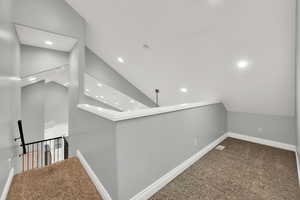 Hallway with lofted ceiling, carpet floors, an upstairs landing, and recessed lighting