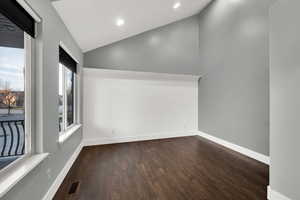 Empty room with lofted ceiling, dark wood-type flooring, and recessed lighting