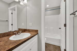 Bathroom featuring vanity, shower / bath combination, and light tile patterned floors