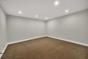 Empty room featuring dark carpet and recessed lighting