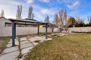Fenced backyard featuring a gazebo, a patio, and a vegetable garden