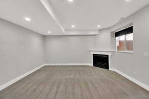 Unfurnished living room featuring a fireplace, recessed lighting, and light carpet