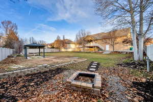 Fenced backyard with a gazebo, a patio, and an outdoor fire pit