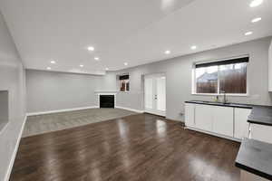 Unfurnished living room featuring french doors, recessed lighting, a fireplace, dark wood-type flooring, and dark carpet