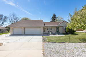 Ranch-style home featuring concrete driveway, a front lawn, an attached garage, and a shingled roof