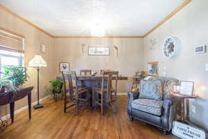 Dining room featuring crown molding, wood finished floors, a chandelier, and a textured ceiling