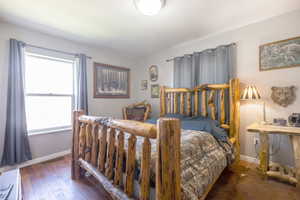 Bedroom featuring dark wood-style flooring and baseboards