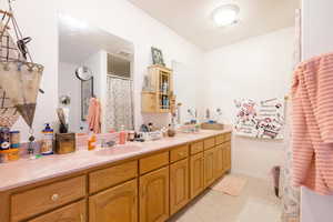 Bathroom featuring curtained shower, double vanity, and light flooring