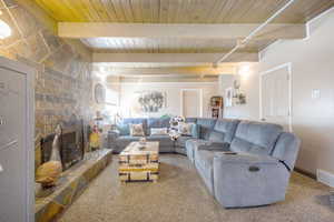Carpeted living room with a fireplace and a wood ceiling with exposed beams