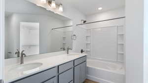 Full bathroom featuring a walk in closet, double vanity, and shower / tub combination