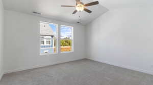 Spare room featuring lofted ceiling, light carpet, and ceiling fan