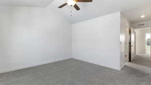 Carpeted empty room featuring a ceiling fan and lofted ceiling
