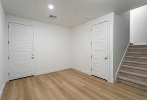 Spare room with stairway and light wood finished floors