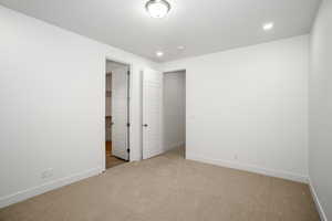 Unfurnished bedroom featuring a spacious closet, light colored carpet, and recessed lighting