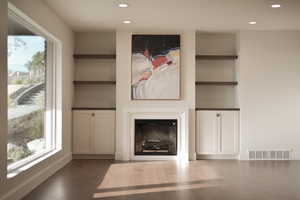 Unfurnished living room featuring built in shelves, a glass covered fireplace, recessed lighting, and dark wood-style flooring