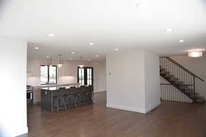 Living room with dark wood-style flooring, recessed lighting, and stairway