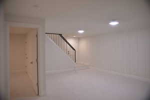 Below grade area with stairs, light colored carpet, and recessed lighting