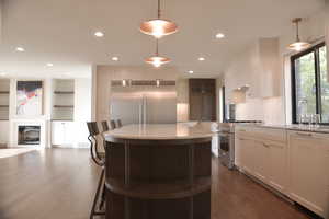 Kitchen featuring high end appliances, white cabinets, glass insert cabinets, plenty of natural light, and recessed lighting